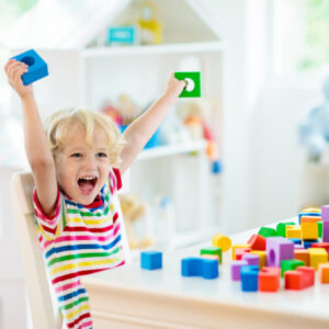 Small child cheering and holding up building blocks