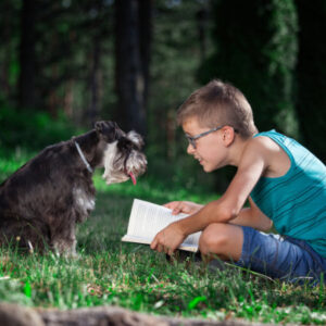 A young boy reading to a terrier