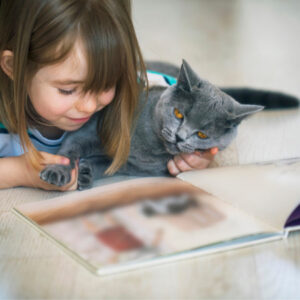 A young girl reading to a cat