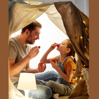 father and child eating in a sheet fort