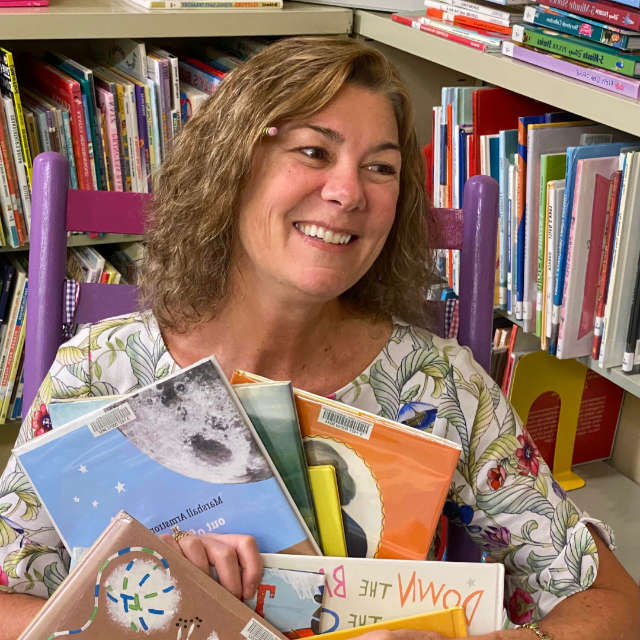 Author Holly DiBella McCarthy surrounded by books
