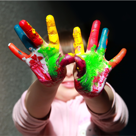 child holding up hands covered in paint